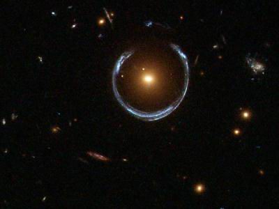 طبق نسبیت عام اینشتین، نور در عبور از نزدیکی اجرام سنگین خم می‌شود. گرانش شدید اجسام فوق‌سنگین مانند کهکشان‌ها می‌تواند تصویری حلقوی از اجسام پشتشان ایجاد کرده و حلقه‌های اینشتین را پدید آورند.